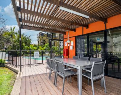 Outdoor BBQ area with seating and grill facilities surrounded by greenery.