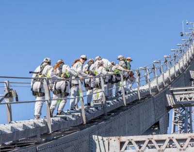 Group of people in safety gear climbing a bridge structure.