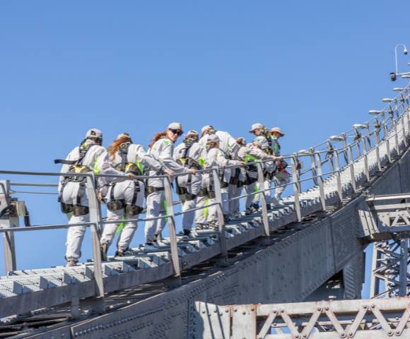 Group of people in safety gear climbing a bridge structure.