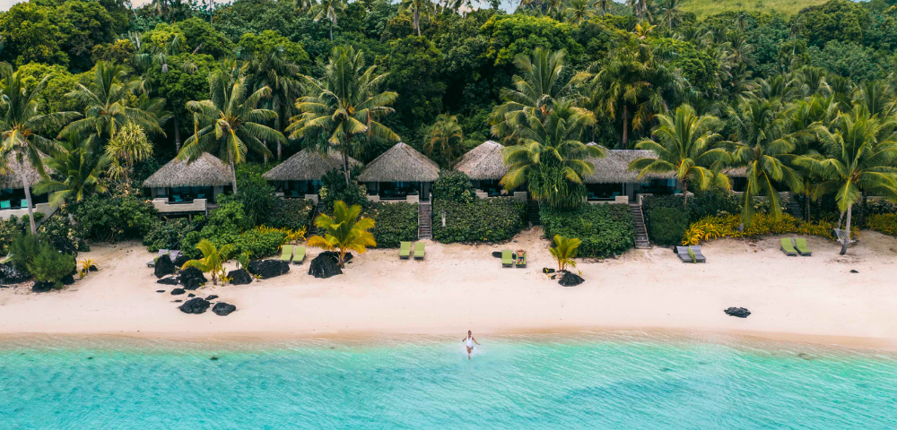 The image features a beautiful beach scene with a person riding a surfboard in the water, enjoying the ocean waves. The surfer is located in the middle of the scene, with the surfboard clearly visible beneath them.