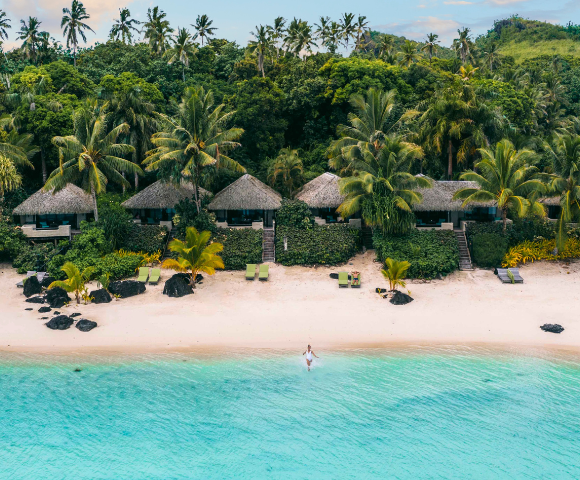 The image features a beautiful beach scene with a person riding a surfboard in the water, enjoying the ocean waves. The surfer is located in the middle of the scene, with the surfboard clearly visible beneath them.