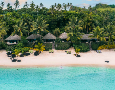 The image features a beautiful tropical beach scene with a person swimming in the crystal blue water. The person is located near the center of the image, enjoying the refreshing water.