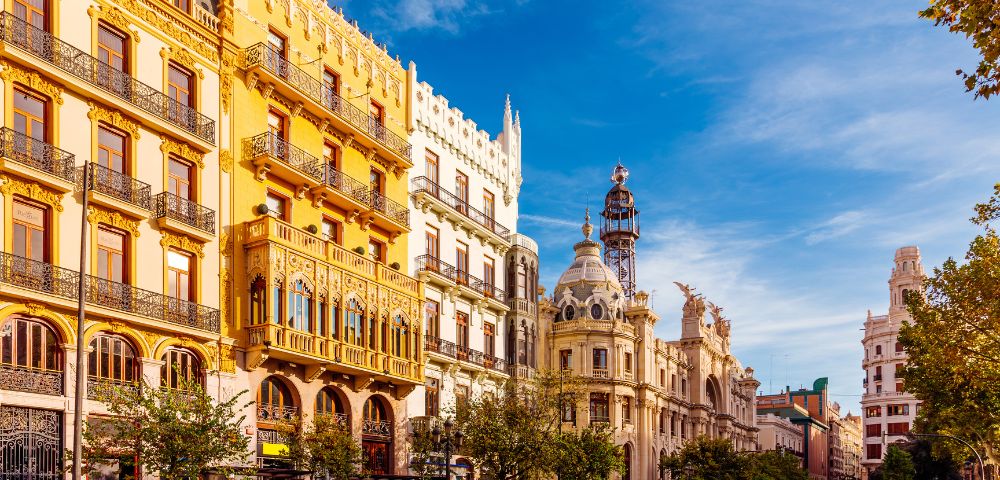 A bright cityscape of Valencia, Spain showcases colorful buildings under a clear blue sky.
