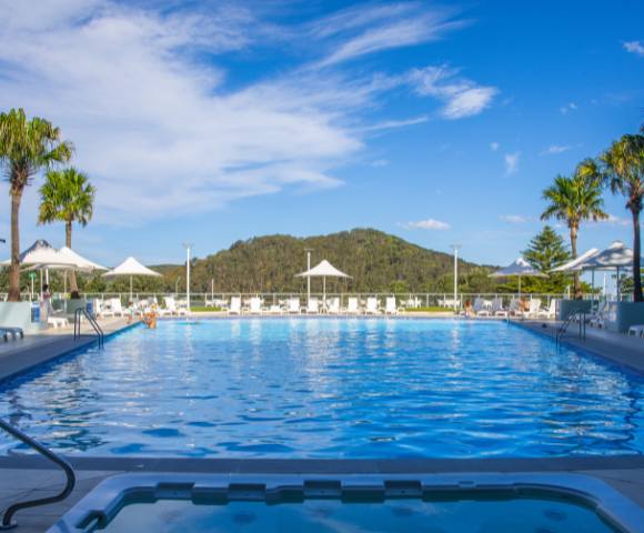 Aerial view of Mantra Ettalong Beach resort featuring a large swimming pool and surrounding buildings