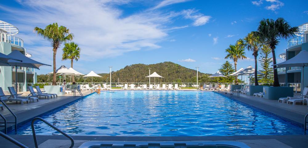 Aerial view of Mantra Ettalong Beach resort featuring a large swimming pool and surrounding buildings