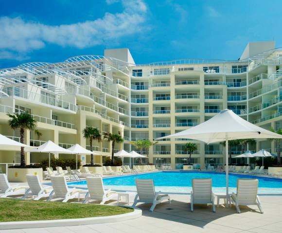 Exterior view of the swimming pool area at Mantra Ettalong Beach with lounge chairs for relaxation