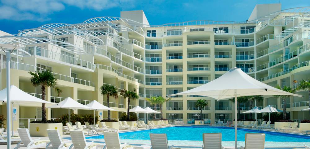 Exterior view of the swimming pool area at Mantra Ettalong Beach with lounge chairs for relaxation