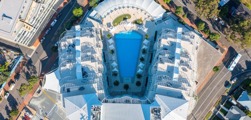 Aerial view of Mantra Ettalong Beach resort featuring a large swimming pool and surrounding buildings