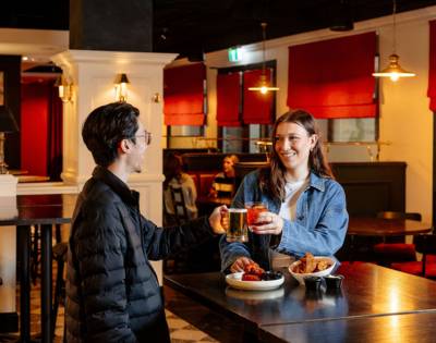 Two people conversing in a casual dining area with red accents and relaxed seating