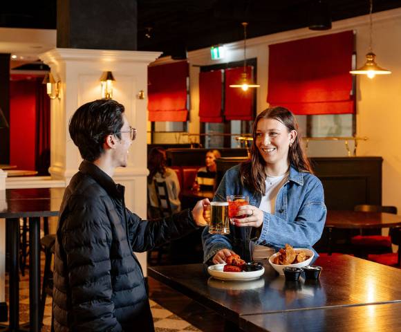 Two people conversing in a casual dining area with red accents and relaxed seating