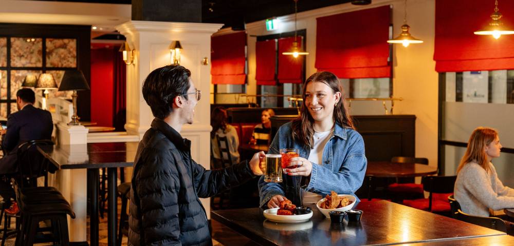 Two people conversing in a casual dining area with red accents and relaxed seating
