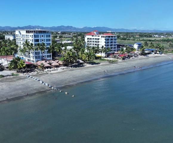 Wide-angle aerial view of a coastal region with multiple buildings and greenery.