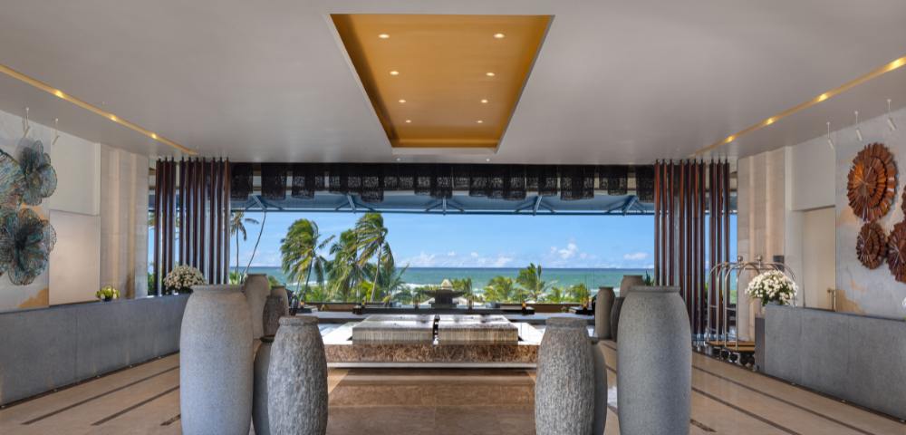 Hotel lobby during daylight hours, featuring sophisticated decor and an open layout with views to the outside.