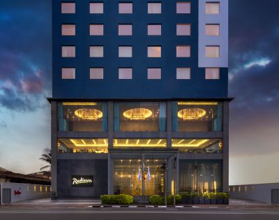 Modern multi-story hotel building illuminated at dusk, featuring sleek architecture and a welcoming entrance.