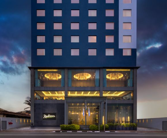 Modern multi-story hotel building illuminated at dusk, featuring sleek architecture and a welcoming entrance.