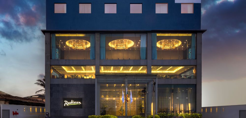 Modern multi-story hotel building illuminated at dusk, featuring sleek architecture and a welcoming entrance.