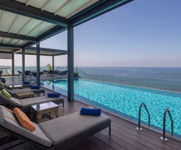 Outdoor infinity pool with lounge chairs under a shaded canopy, overlooking the ocean for a luxurious and tranquil experience.