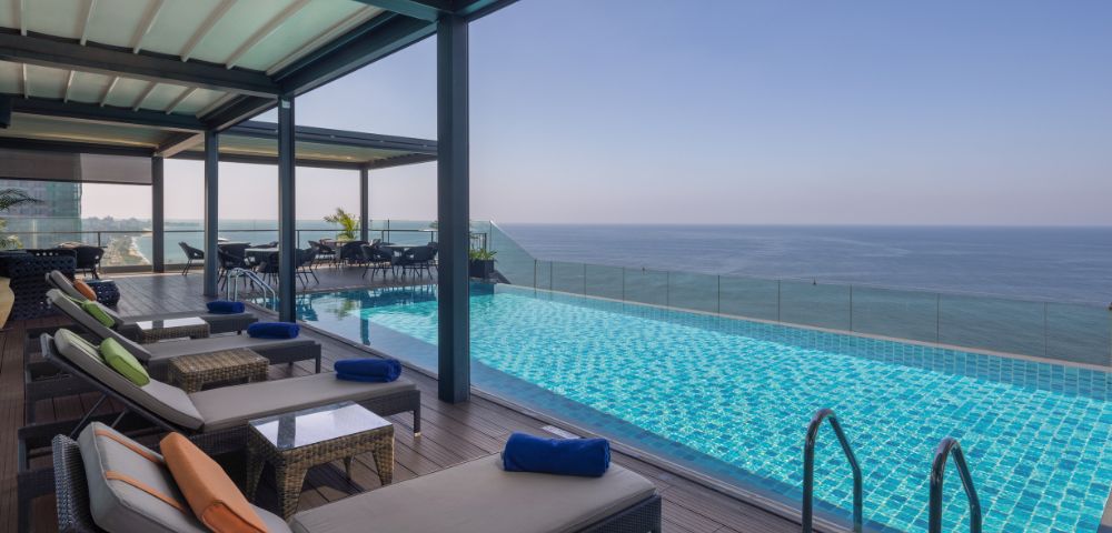 Outdoor infinity pool with lounge chairs under a shaded canopy, overlooking the ocean for a luxurious and tranquil experience.
