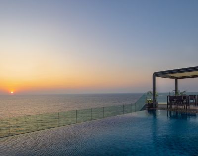 Stunning sunset over the ocean viewed from a wooden deck extending into the water, creating a peaceful and picturesque setting.