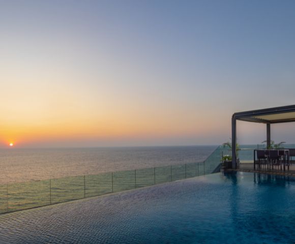 Stunning sunset over the ocean viewed from a wooden deck extending into the water, creating a peaceful and picturesque setting.