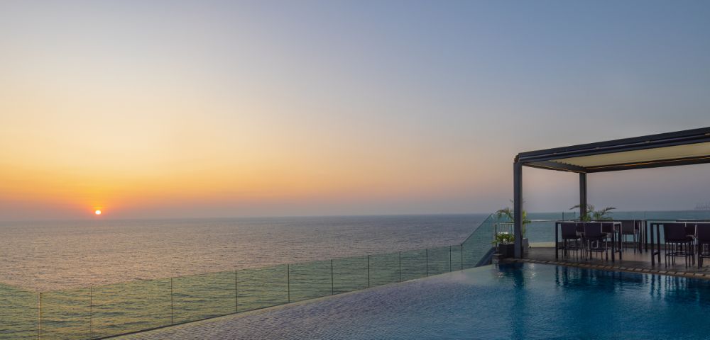 Stunning sunset over the ocean viewed from a wooden deck extending into the water, creating a peaceful and picturesque setting.