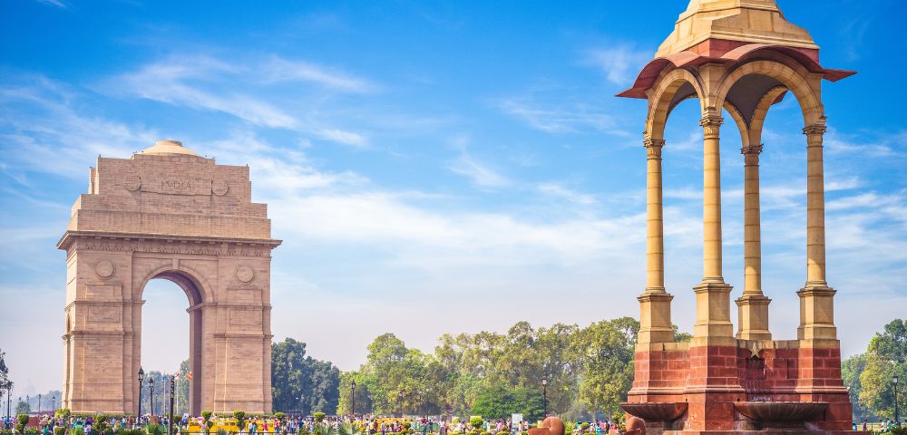 The India Gate war memorial and the nearby canopy structure in New Delhi during daylight.