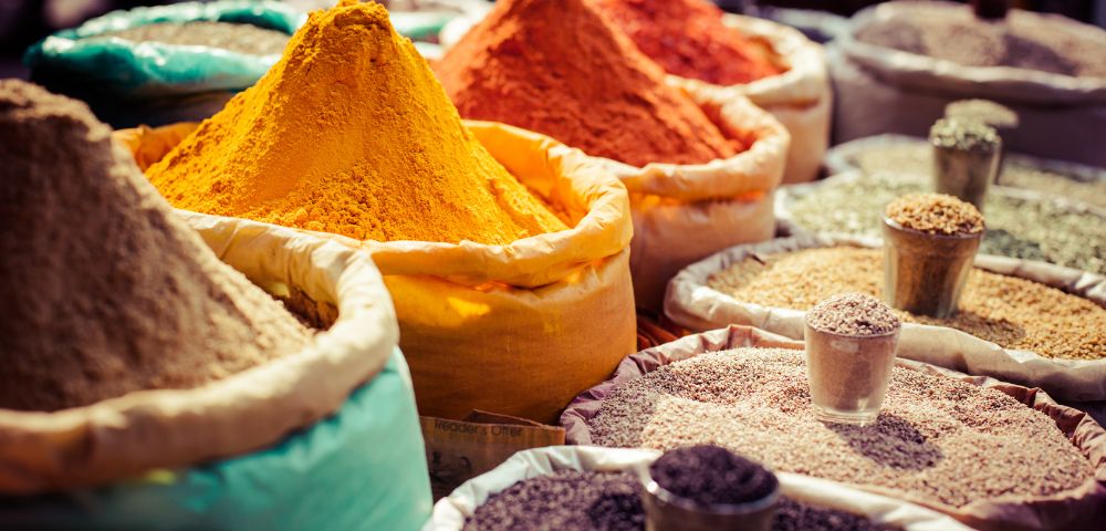 A colorful assortment of Indian spices displayed in bowls and cones at a market