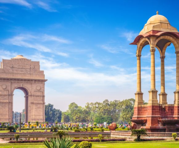The India Gate war memorial and the nearby canopy structure in New Delhi during daylight.
