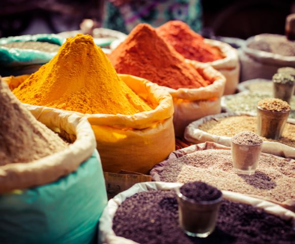 A colorful assortment of Indian spices displayed in bowls and cones at a market