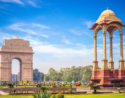 The India Gate war memorial and the nearby canopy structure in New Delhi during daylight.