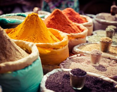 A colorful assortment of Indian spices displayed in bowls and cones at a market