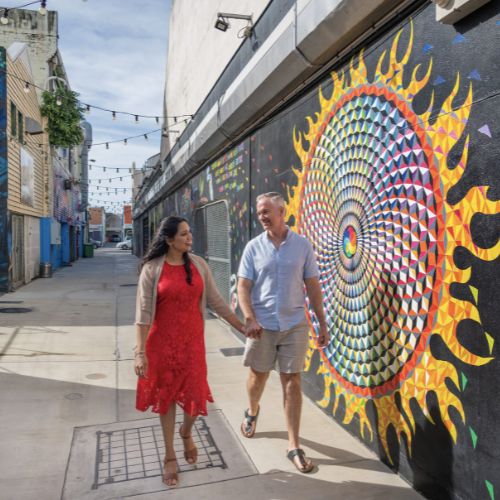 Vibrant street art on an urban wall with a person walking past.