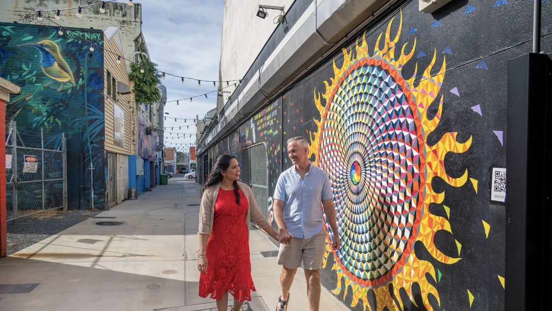 Vibrant street art on an urban wall with a person walking past.
