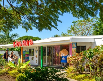 Exterior view of a kids’ club building surrounded by greenery.