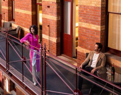Person seated on a balcony at InterContinental Melbourne The Rialto, enjoying the view of the heritage building’s red brick exterior.