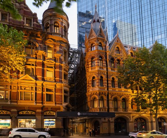 Evening view of InterContinental Melbourne The Rialto’s illuminated Gothic-style architecture with warm lighting against a dusky sky.