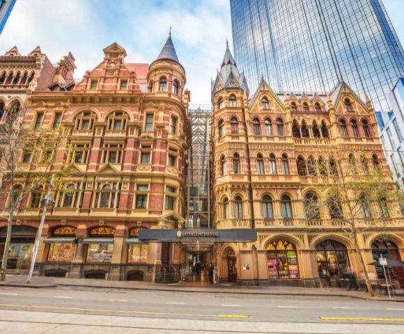 Main entrance of InterContinental Melbourne The Rialto showcasing its historic facade with intricate stone carvings and tall windows.