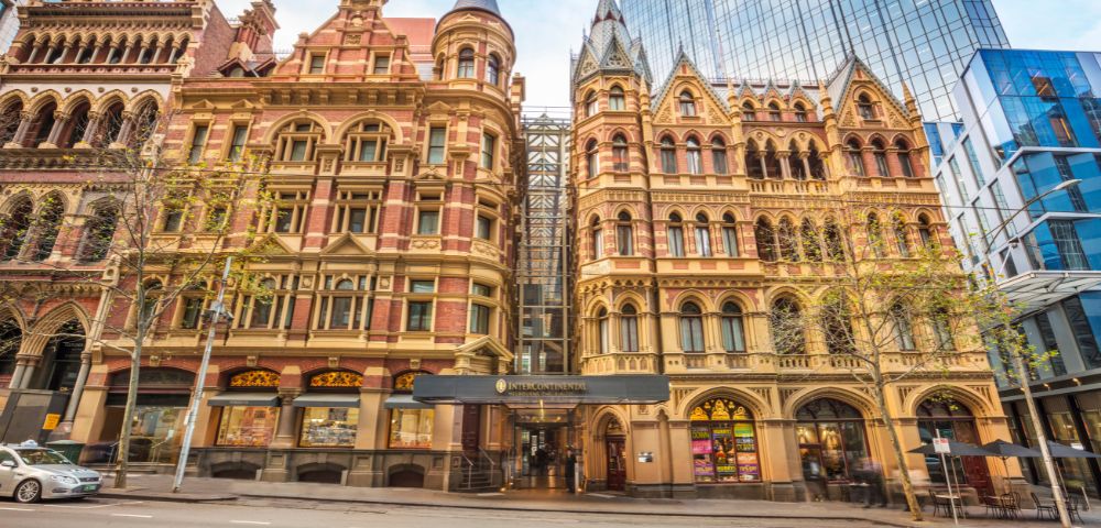 Main entrance of InterContinental Melbourne The Rialto showcasing its historic facade with intricate stone carvings and tall windows.