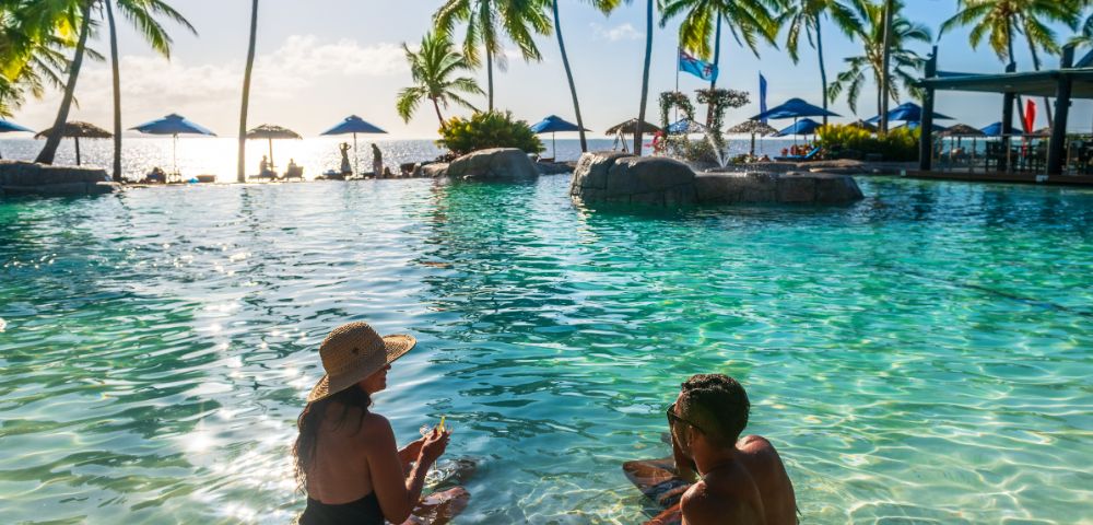 Guests enjoying cocktails at an outdoor bar with ocean views at DoubleTree Resort by Hilton Hotel Fiji.