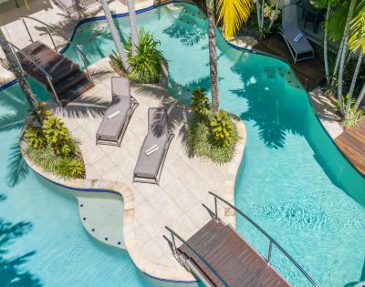 Aerial view of resort pool area with lush gardens and multiple lounging spaces.