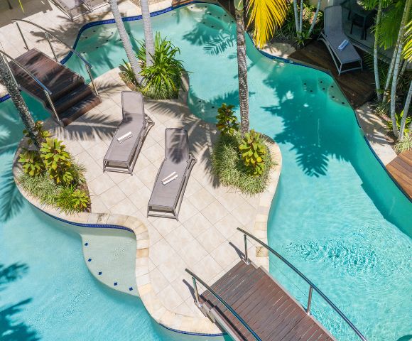 Aerial view of resort pool area with lush gardens and multiple lounging spaces.