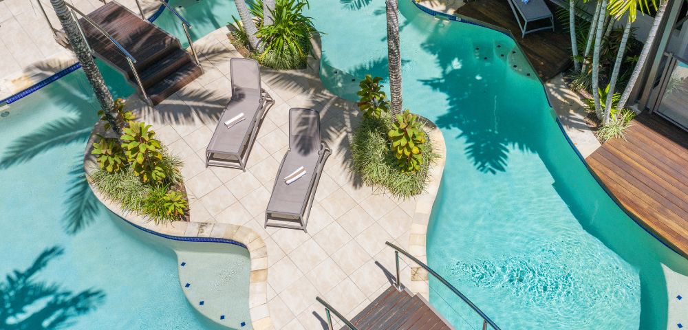 Aerial view of resort pool area with lush gardens and multiple lounging spaces.