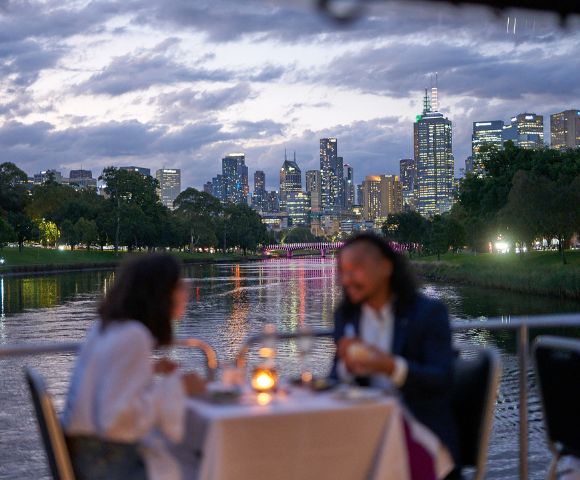 Romantic dinner setting on a river cruise with sunset view over Melbourne.