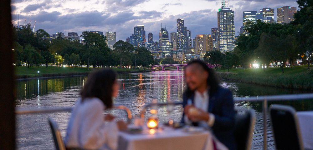 Romantic dinner setting on a river cruise with sunset view over Melbourne.