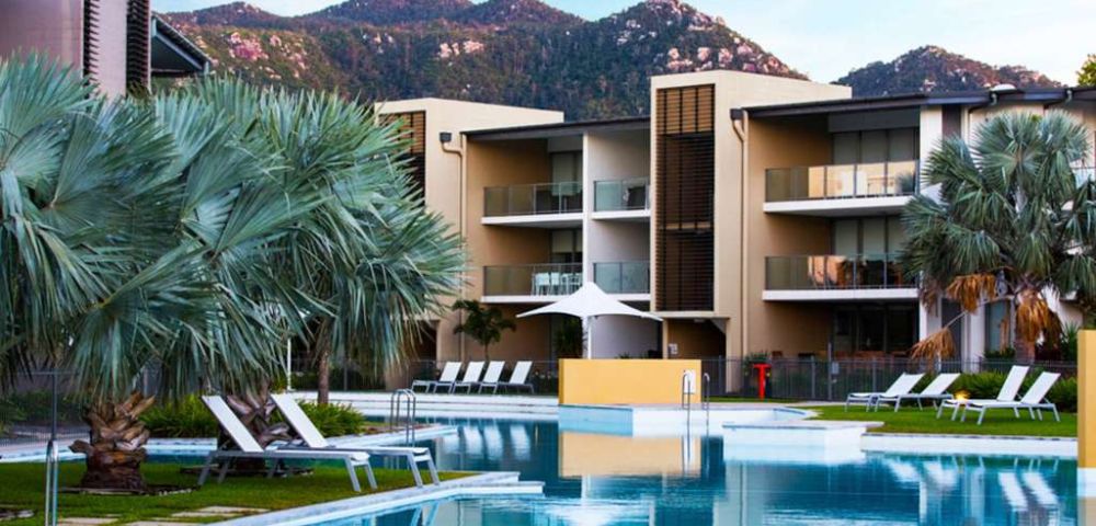 3. Bright, minimalist bathroom with a large mirror reflecting a modern sink, chrome faucet, and white towels. The atmosphere is clean and serene.