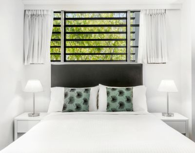 Bright, minimalist bathroom with a large mirror reflecting a modern sink, chrome faucet, and white towels. The atmosphere is clean and serene.