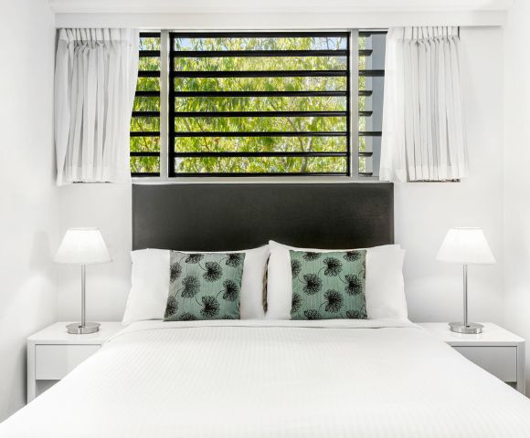 Bright, minimalist bathroom with a large mirror reflecting a modern sink, chrome faucet, and white towels. The atmosphere is clean and serene.