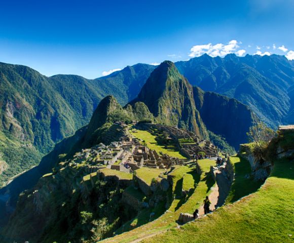 The ancient Incan city of Machu Picchu nestled among towering green mountains. Stone terraces and historic structures highlight its archaeological significance.