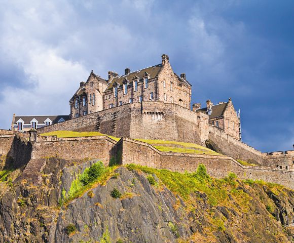 A majestic medieval castle perched on a rocky hill, with stone walls and turrets. Sunlit, under a dramatic, cloudy sky, evoking strength and history.