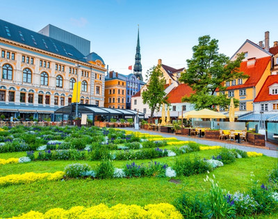 A vibrant European cityscape with ornate historical buildings, a lush garden in the foreground, and colorful facades under a clear blue sky, exuding charm.